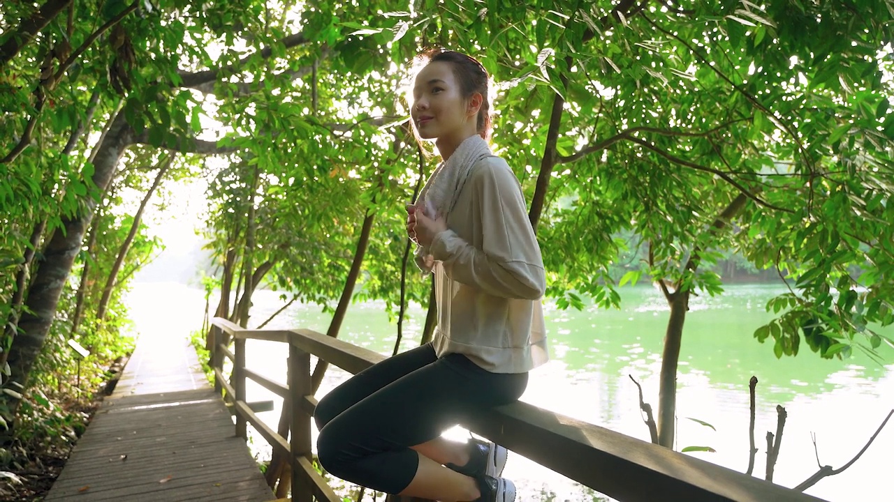 一名亚裔华人在自然保护区公园的木桥上休息视频下载