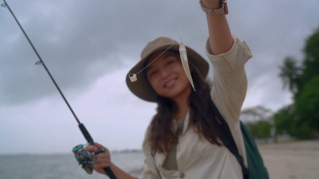 一名亚裔中国妇女在海滩上钓到了一条小鱼视频下载