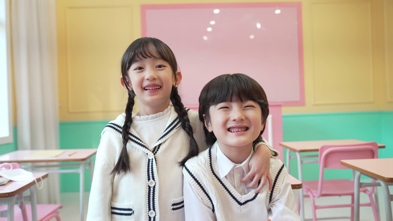 幼儿园和小学的新学期——男孩和女孩挽着彼此的肩膀，对着镜头微笑视频下载