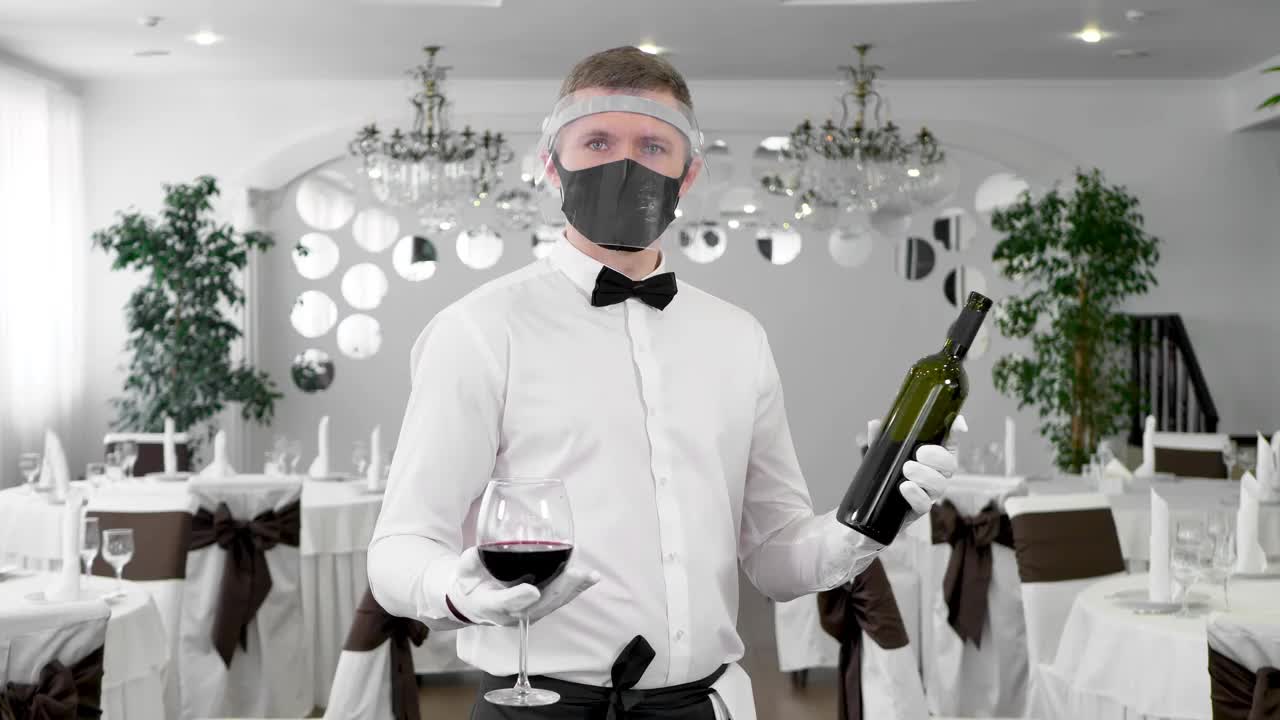 服务员戴着防护面具，手里拿着一杯红酒视频素材
