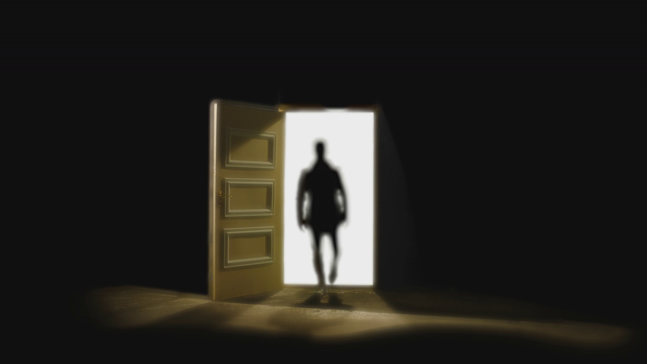 4K前视图的人走在前面的一扇敞开的门后面的黑暗。有人在地板上行走的镜头。白色的光在门里面。匿名的概念，精神昏迷或瞬间移动视频下载