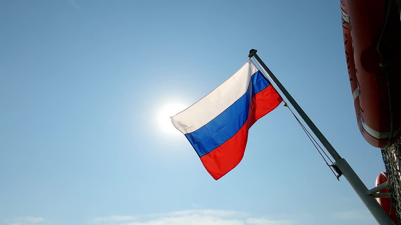 俄罗斯国旗在天空和太阳圆盘的背景下飘扬视频素材