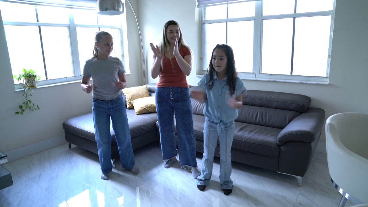 母亲带着女儿和朋友在客厅愉快地练习舞蹈视频下载