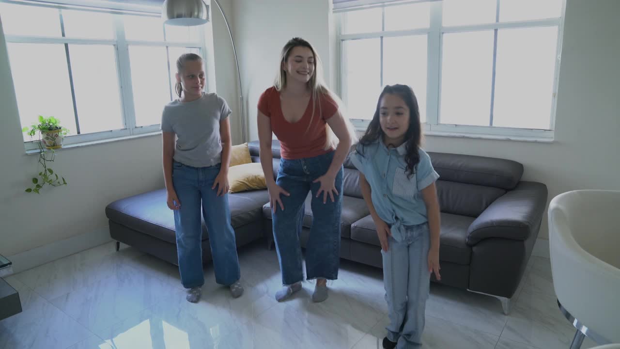 母亲带着女儿和朋友在客厅愉快地练习编舞视频下载
