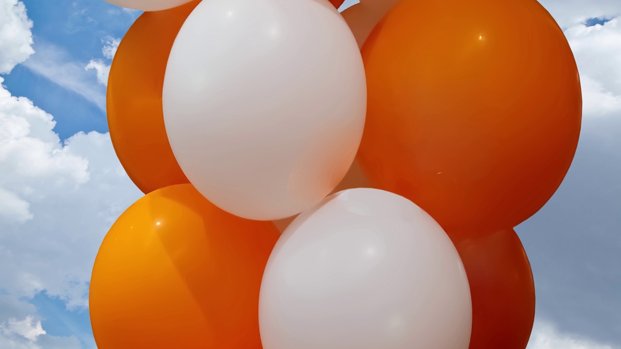 白色和橙色的气球漂浮在云层和天空的背景下视频下载