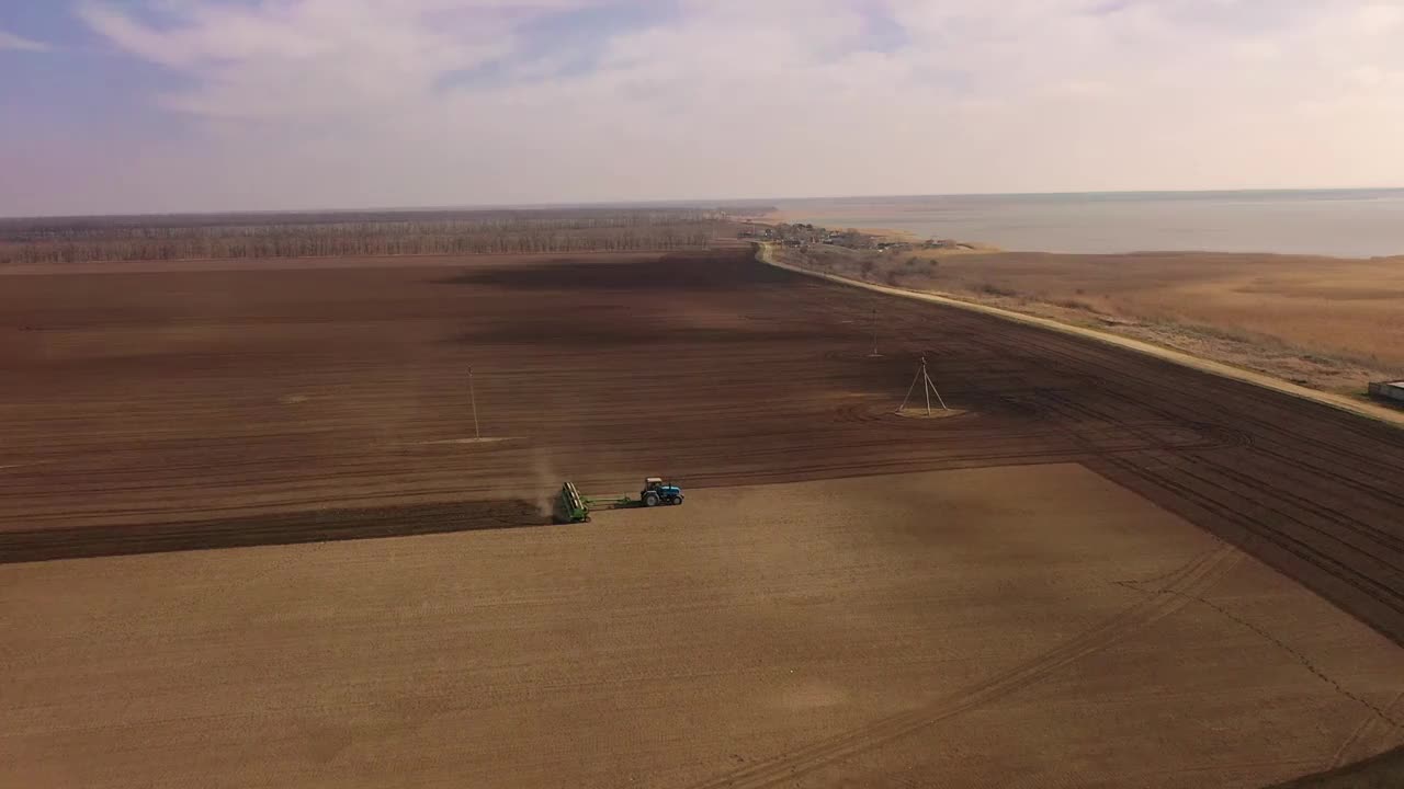 拖拉机式播种机在试验田的土壤中播种。鸟瞰图视频下载