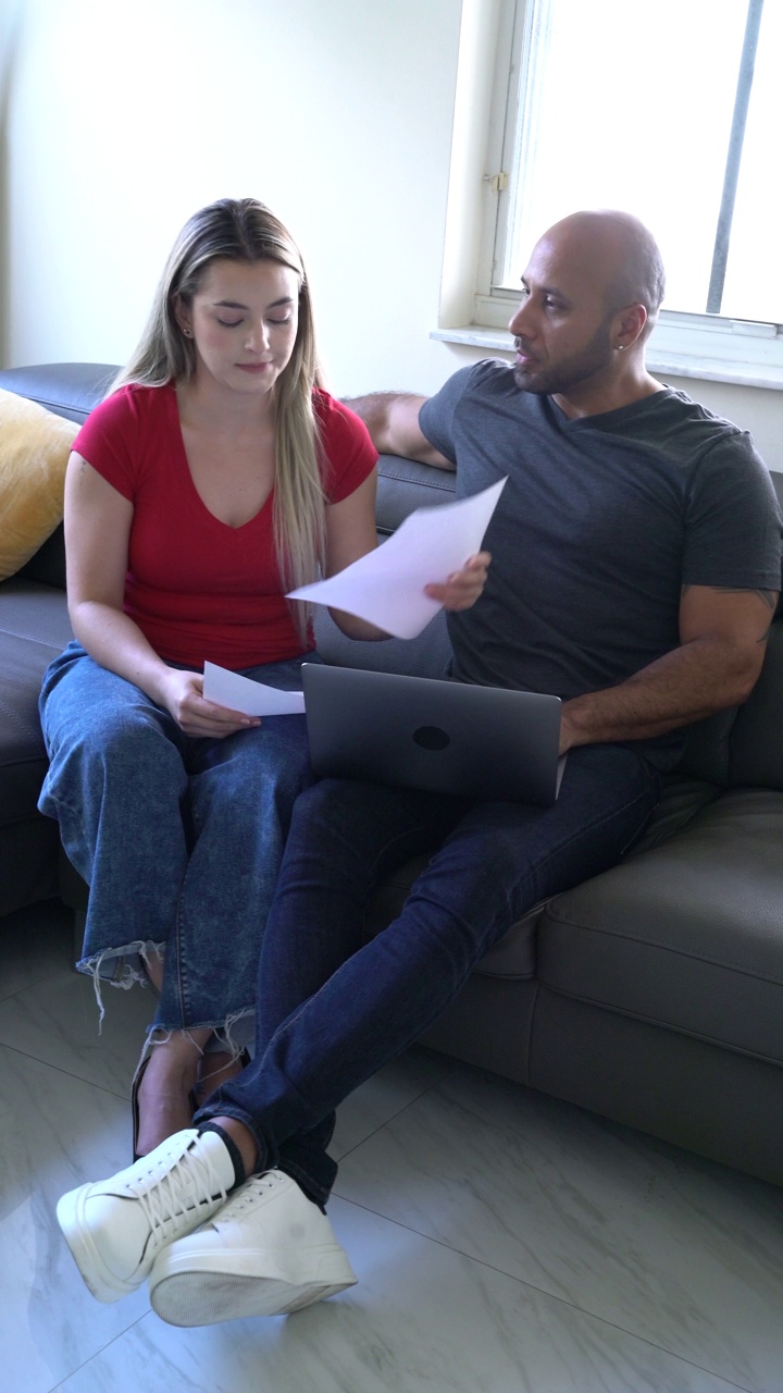 夫妻俩在客厅沙发上用笔记本电脑看笔记和个人数据视频下载