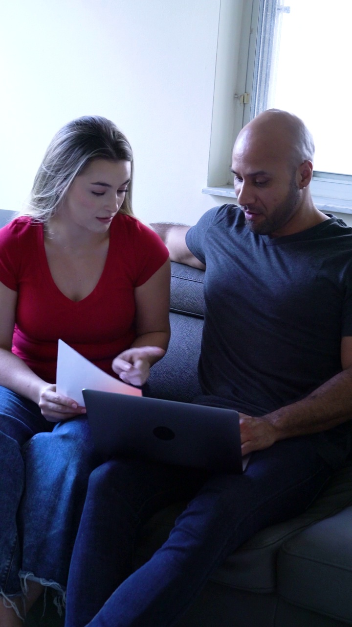夫妻俩在客厅沙发上用笔记本电脑看笔记和个人数据视频下载