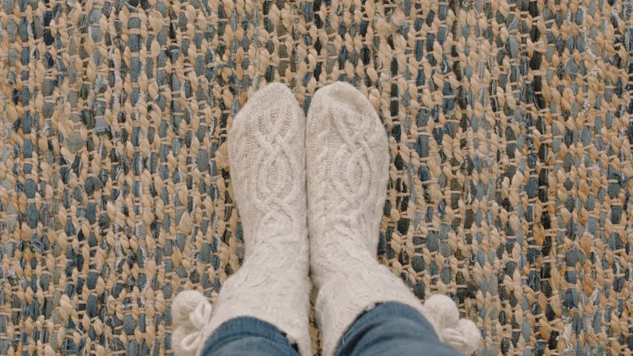 俯视图脚穿着舒适的袜子享受温暖在地毯地毯上的家视频下载