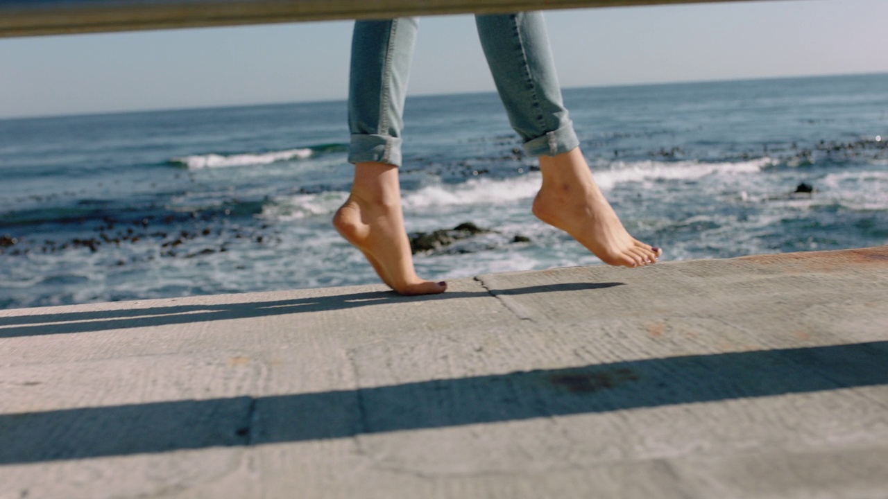女人的腿赤脚走在海边码头平衡少年享受暑假在美丽的海洋背景视频下载