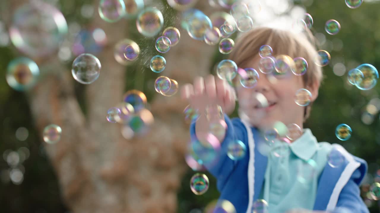 快乐的小男孩顽皮地抓肥皂泡漂浮与可爱的孩子玩在阳光灿烂的公园无忧无虑的童年游戏泡泡4k视频下载