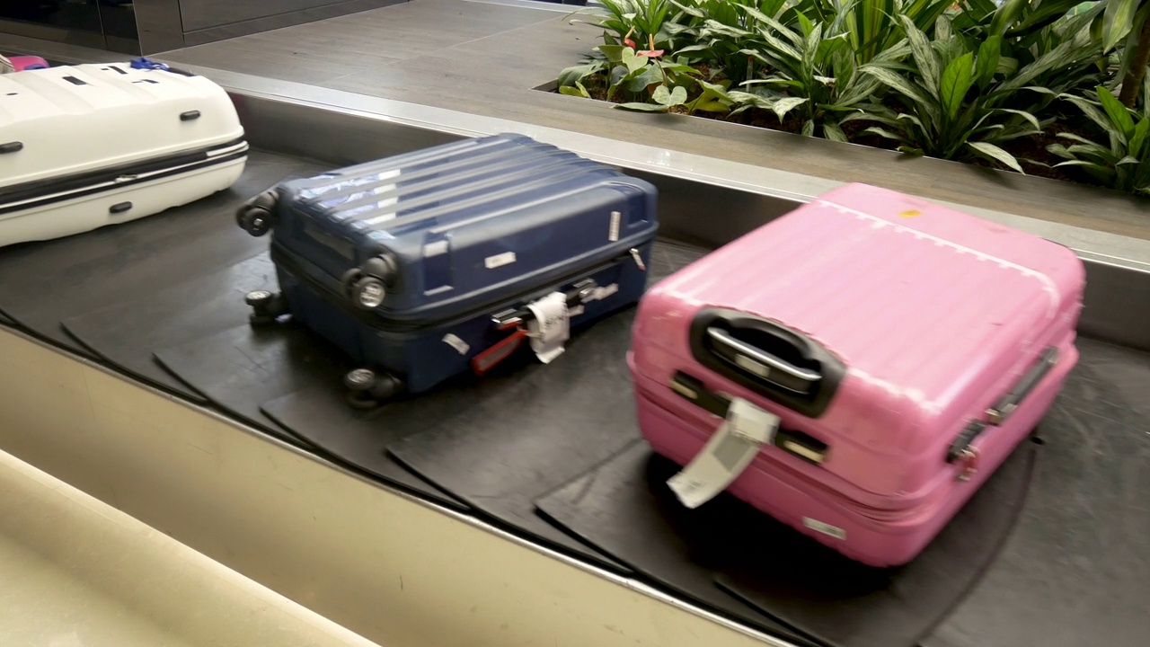 办理国际机场到达旅客的行李提取手续。机场传送带上的各种行李箱。行李在传送带上运输视频下载