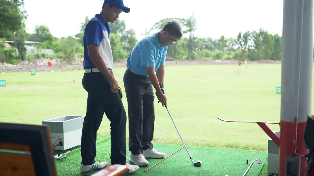 活跃的资深亚裔华人高尔夫球手在练习场开球和挥杆视频下载
