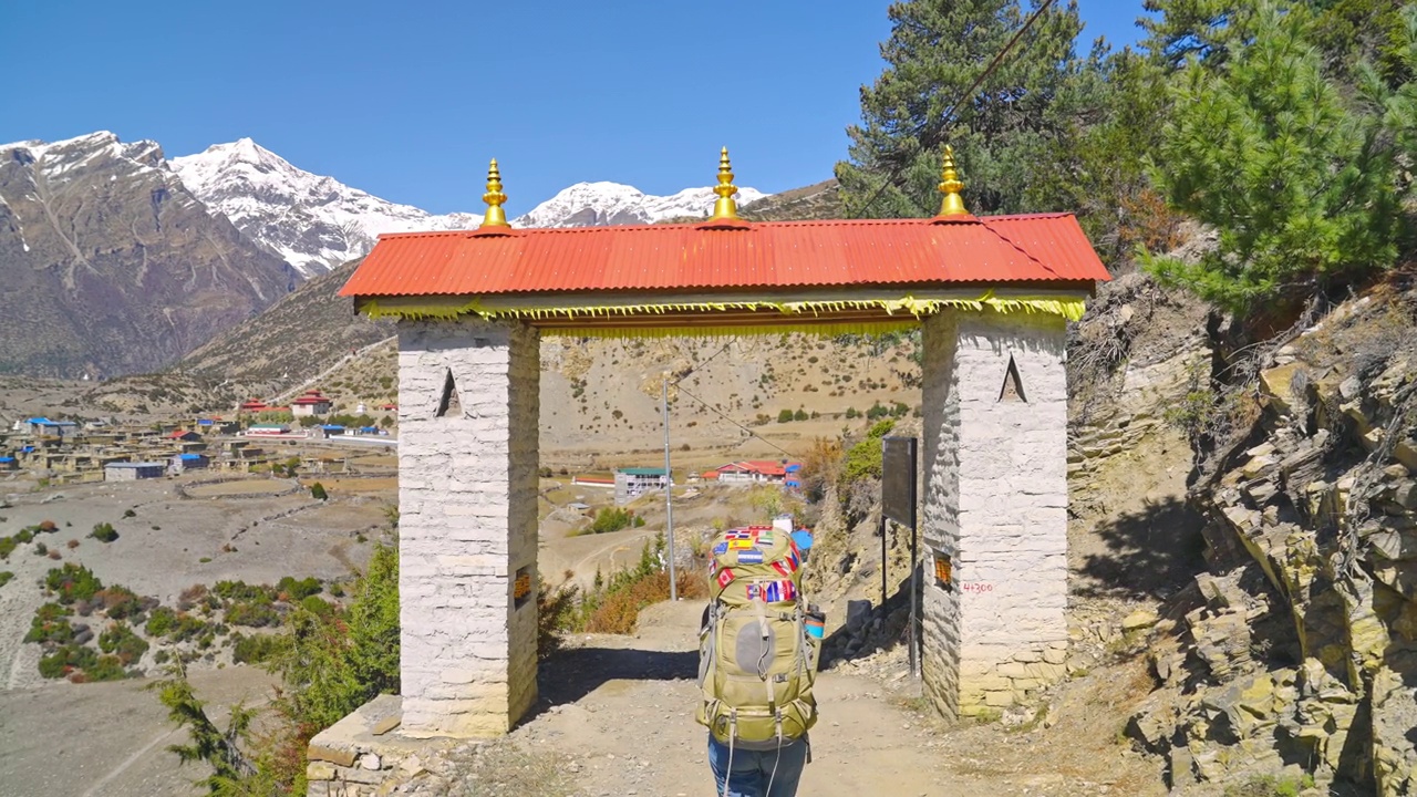 尼泊尔安纳普尔纳环行，徒步旅行者穿过喜马拉雅山脉的传统村庄大门视频素材