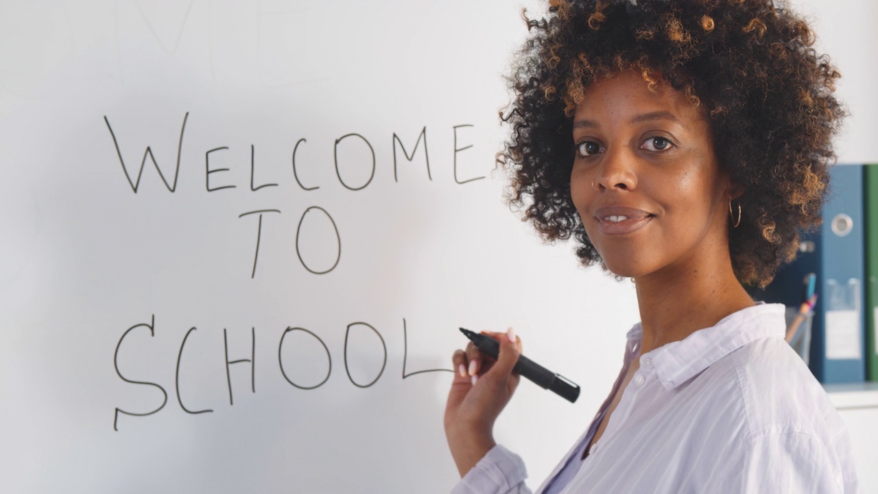 非裔美国年轻女教师在教室的白板上写欢迎来到学校视频下载