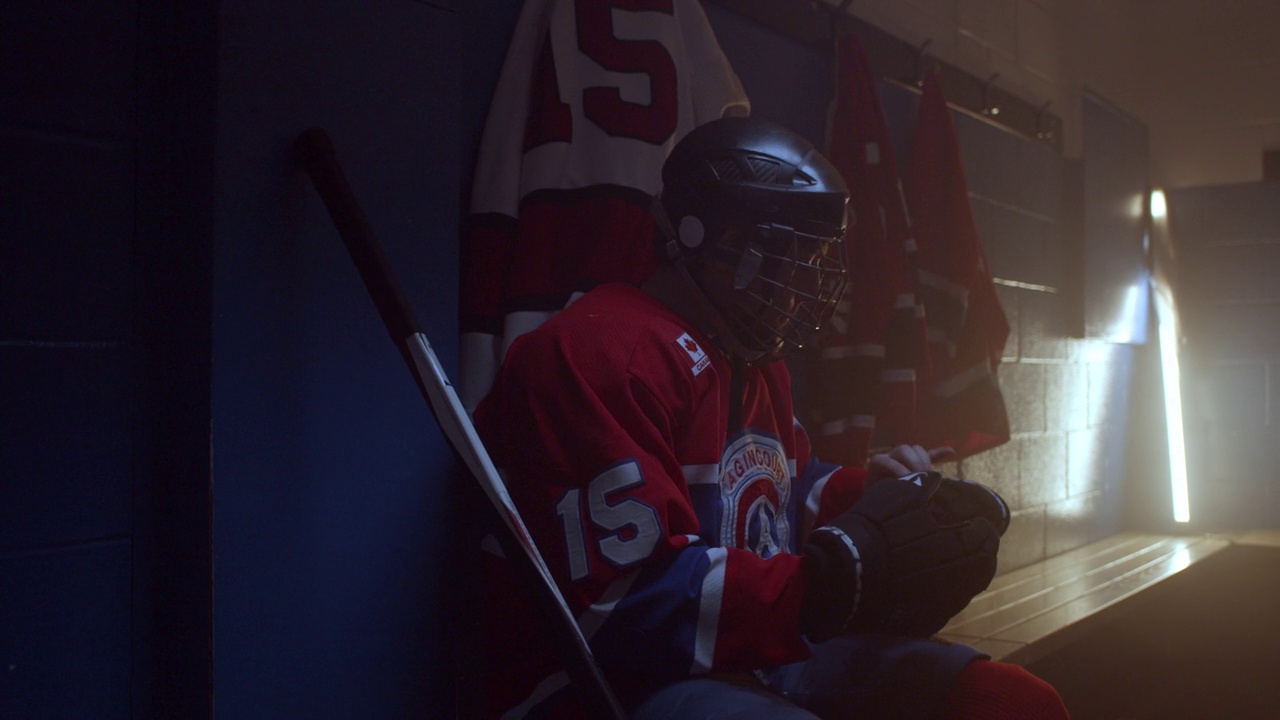 身穿红色制服的冰球运动员在更衣室里严肃地准备着视频素材