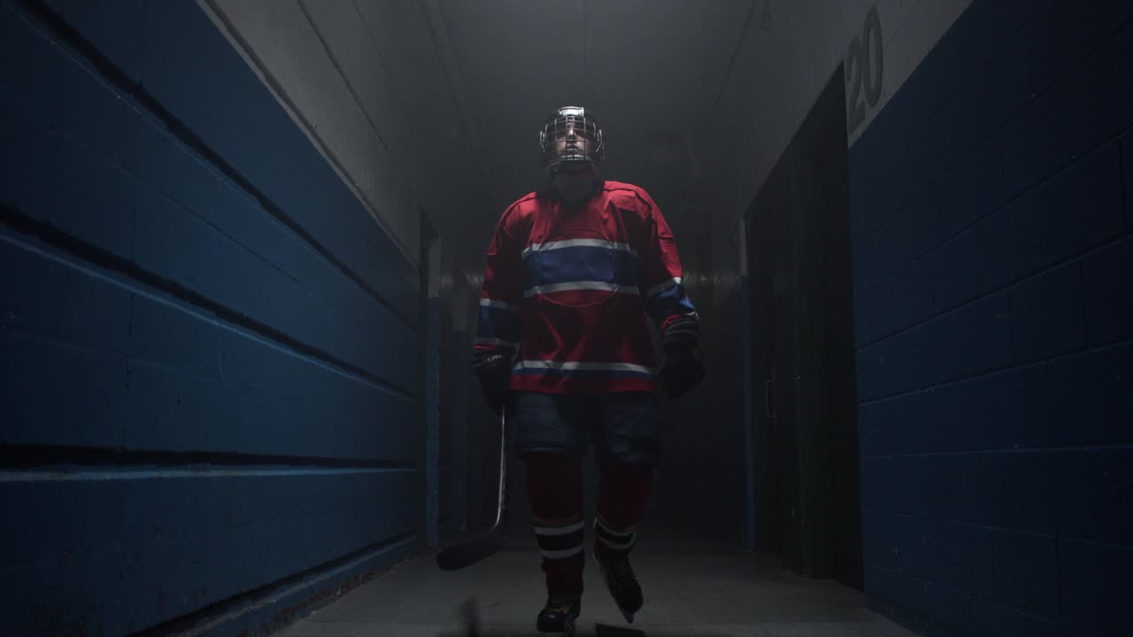 曲棍球运动员在红色制服走在黑暗的走廊在竞技场视频素材