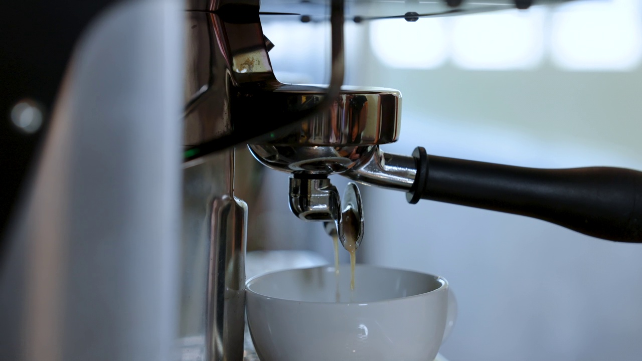 它将咖啡柄插入咖啡机，以便等待咖啡萃取机变成咖啡汁，将热咖啡饮用在适合热菜单的小杯中。视频素材