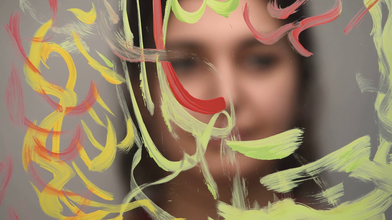 艺术家用画笔和彩色颜料在窗户玻璃上作画视频下载