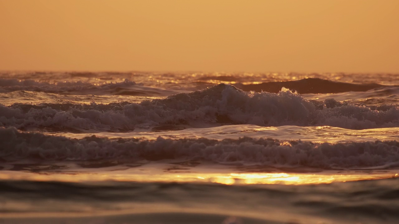 日出时，海浪拍打着海岸。慢动作视频素材