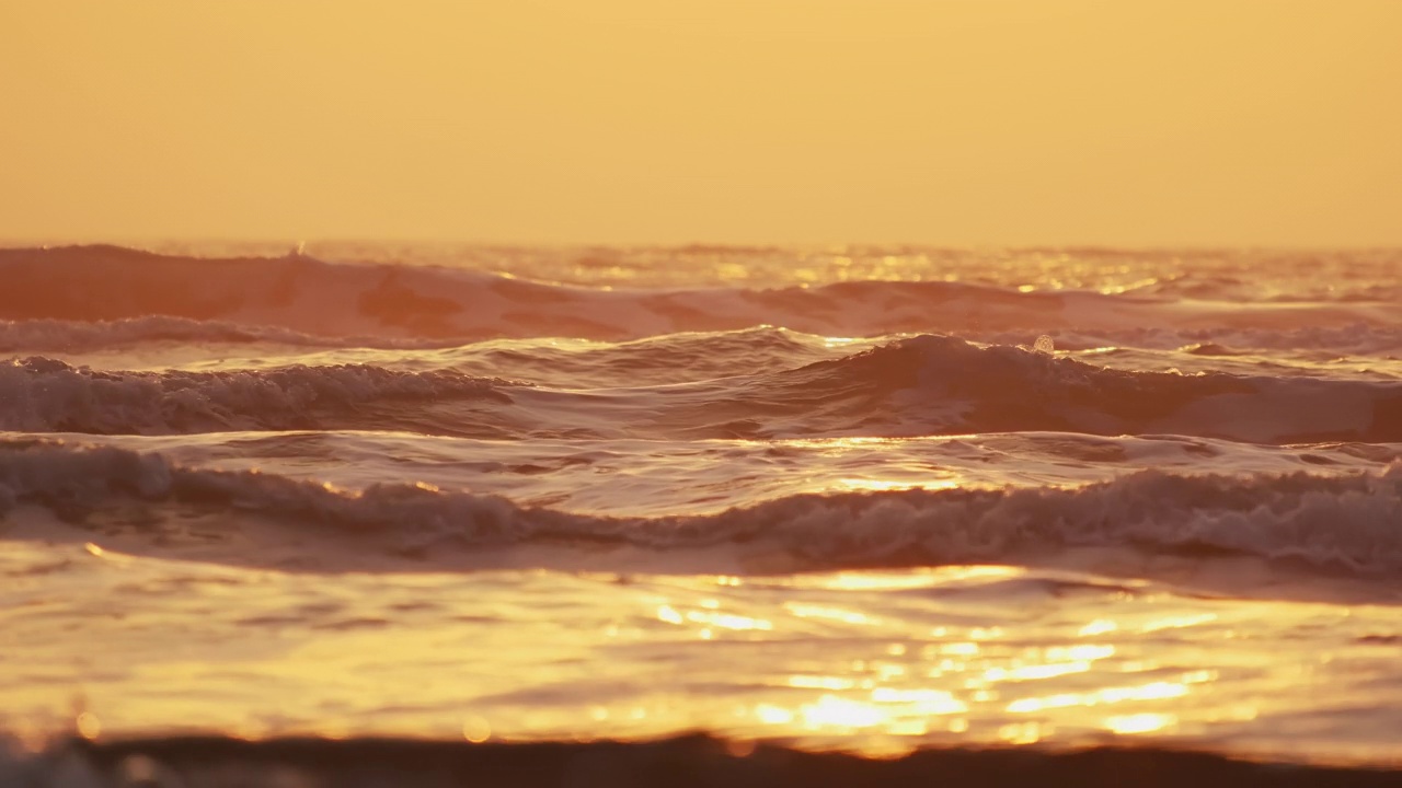 日出时海浪拍打海岸的特写。慢镜头视频素材