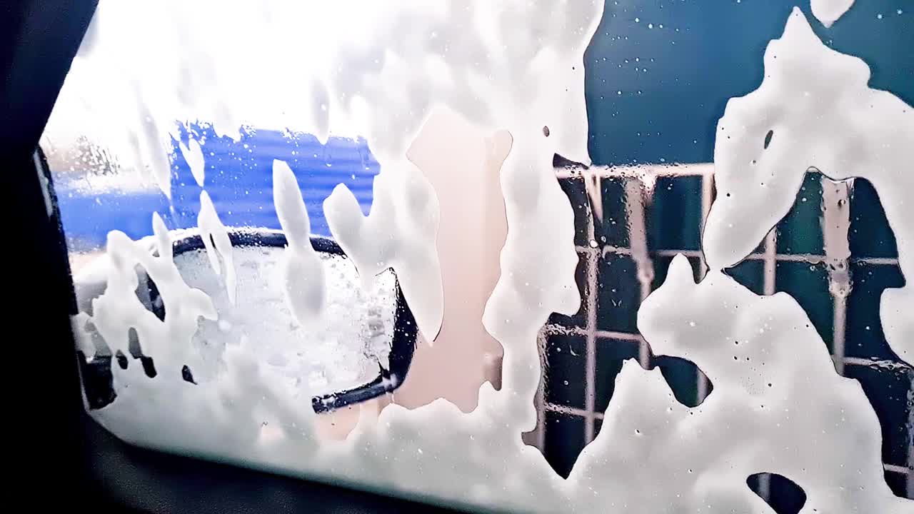 洗车。洗车泡沫顺着汽车的侧窗流下。视频素材
