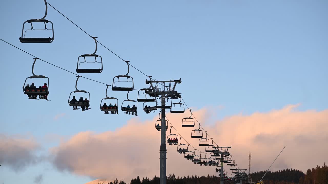 滑雪者和单板滑雪者从雪坡上乘电梯到下一个滑雪场视频下载