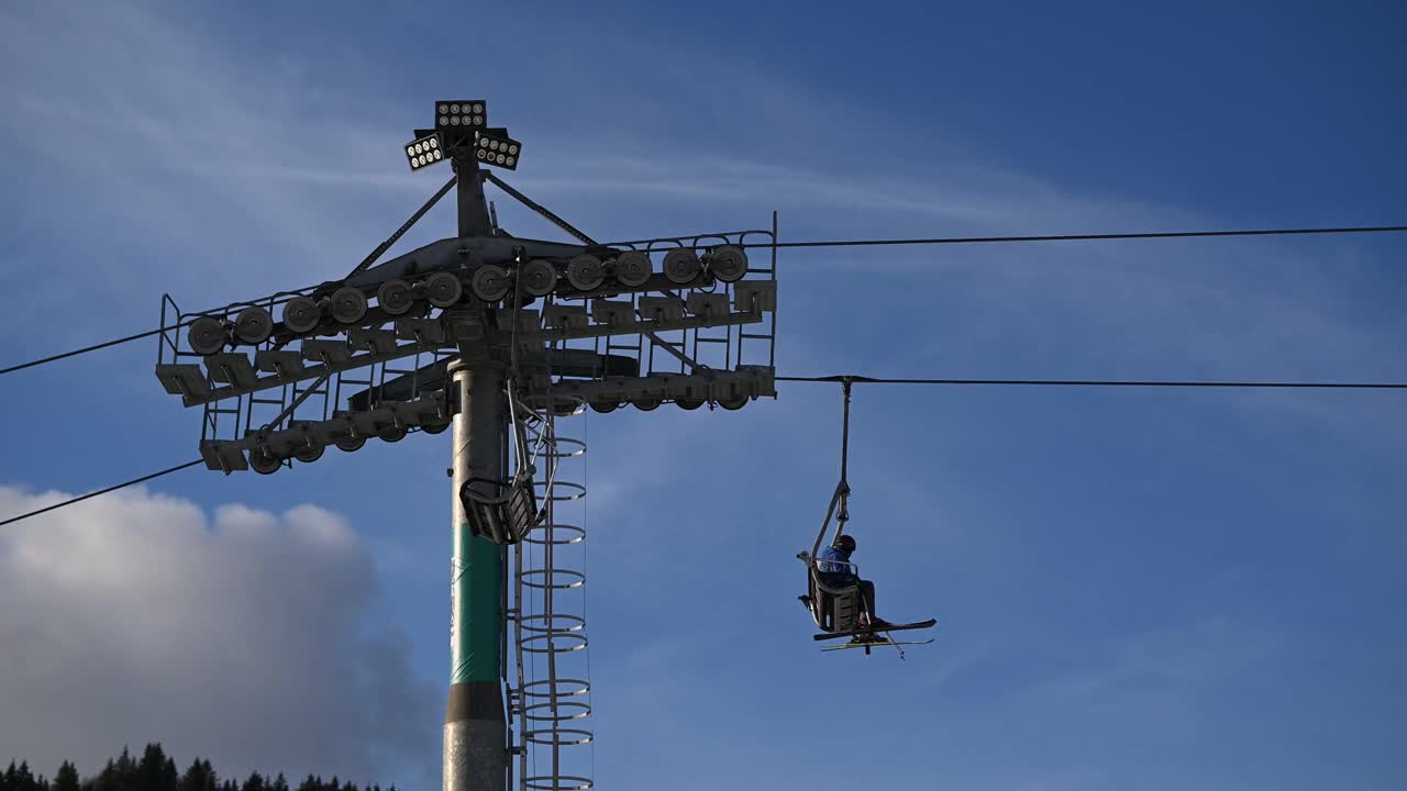 滑雪者和单板滑雪者从雪坡上乘电梯到下一个滑雪场视频下载