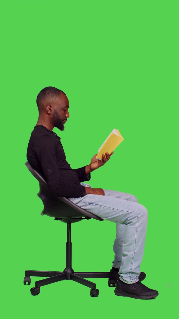 垂直视频:专注的人在工作室读故事书的侧面视频下载