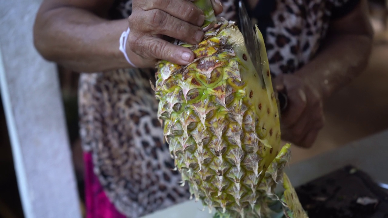 一个女人用一把大刀削菠萝的特写视频下载