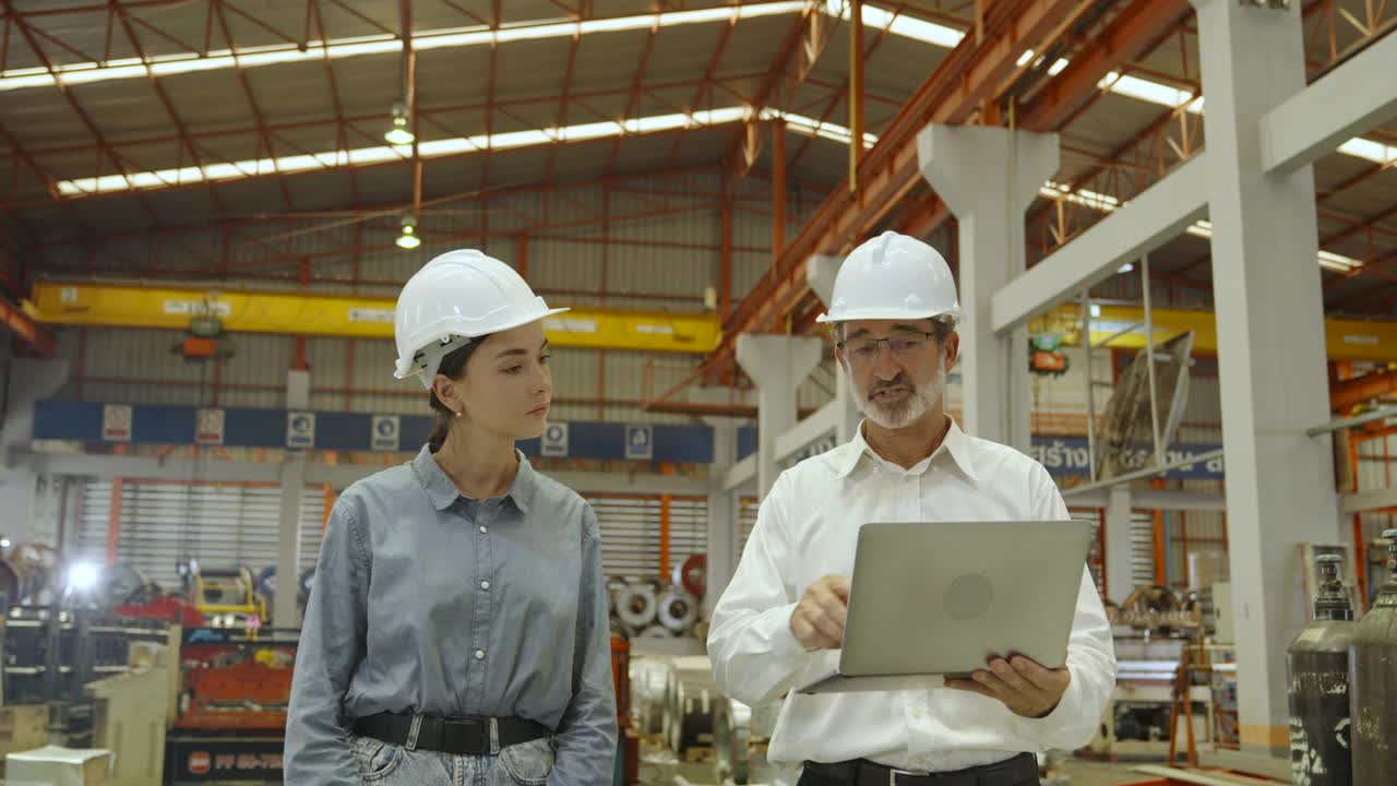 重工业工程师男女走在工厂里检查生产线。视频下载