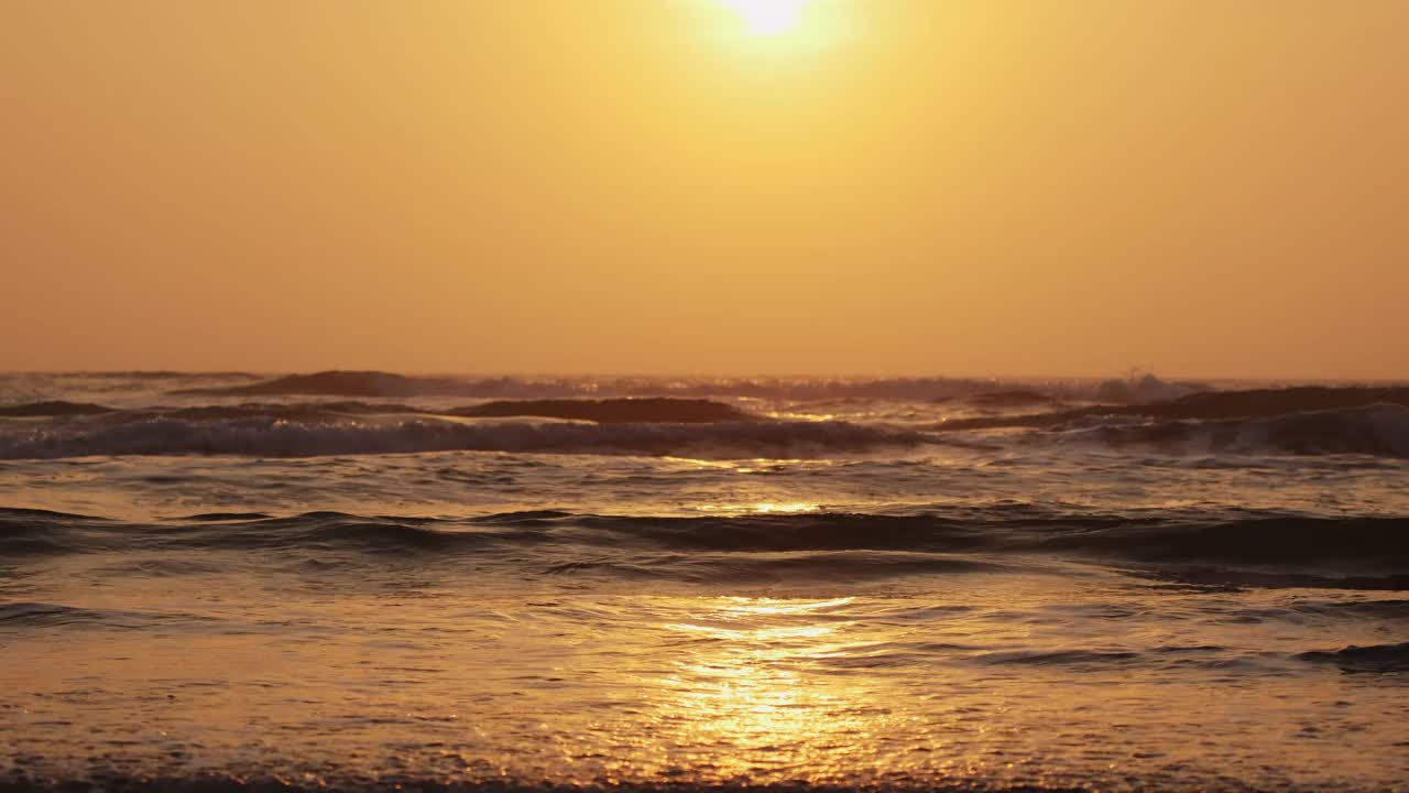 金色日出时，海浪拍打着海岸。慢镜头镜头视频素材