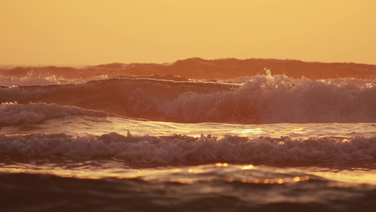 海浪在日出时撞击海岸的特写。慢镜头镜头视频素材