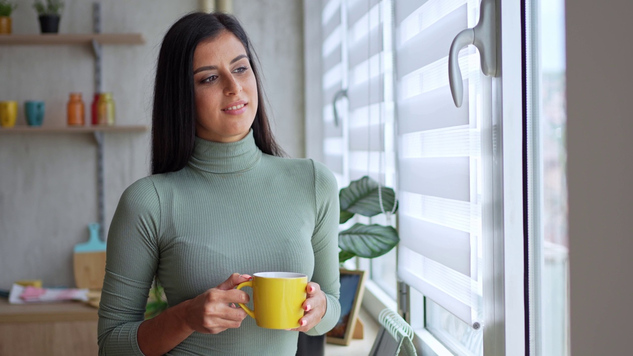 女人一边喝咖啡一边往窗外看视频素材