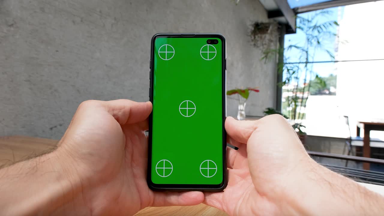 男性双手垂直手持智能手机，绿色屏幕，向上滑动屏幕。视频下载