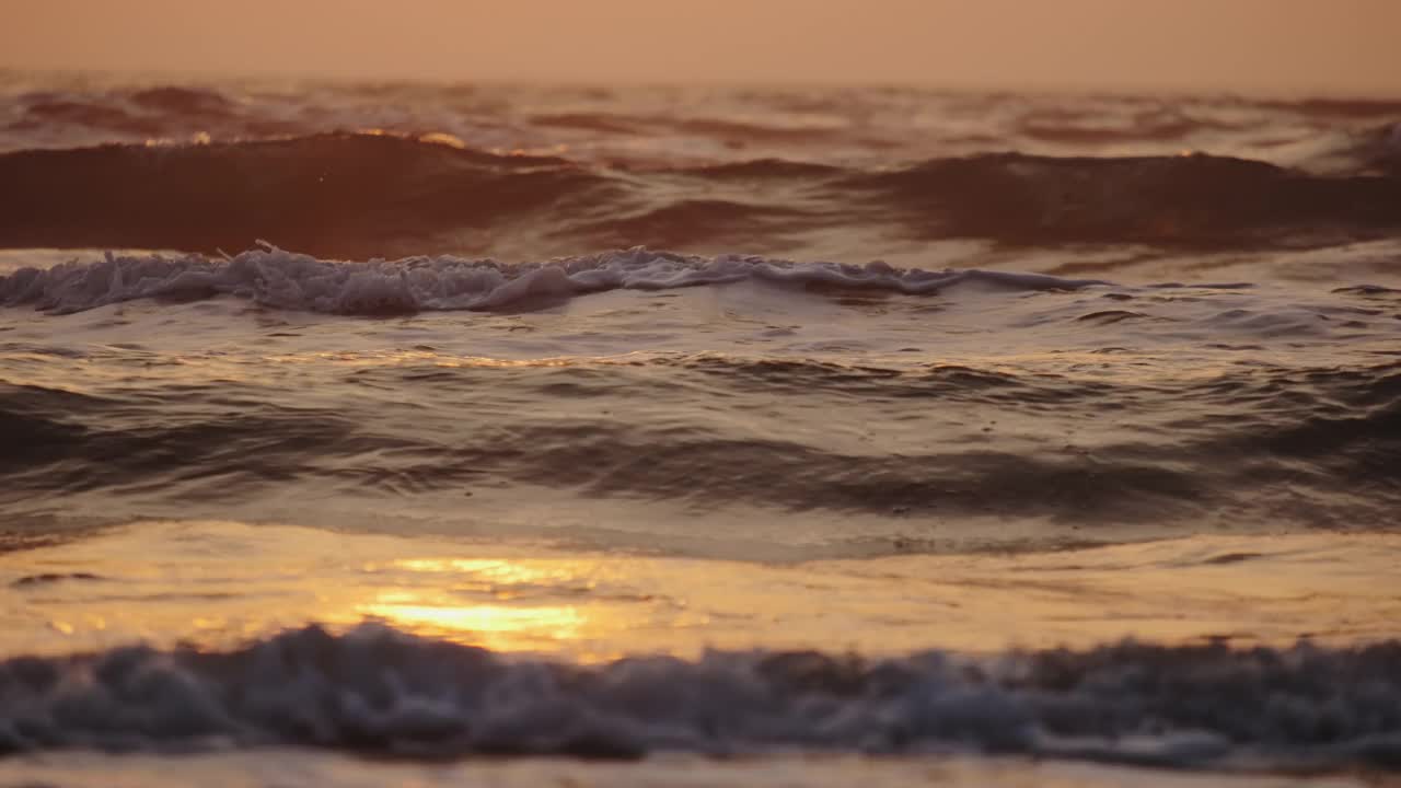 日出时，海浪拍打着海岸。慢动作镜头视频素材