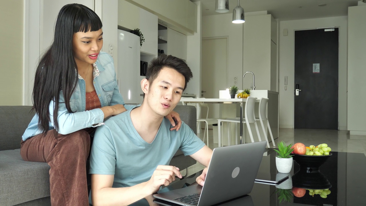 泛亚夫妇在家里用笔记本电脑远程工作或网上购物视频素材