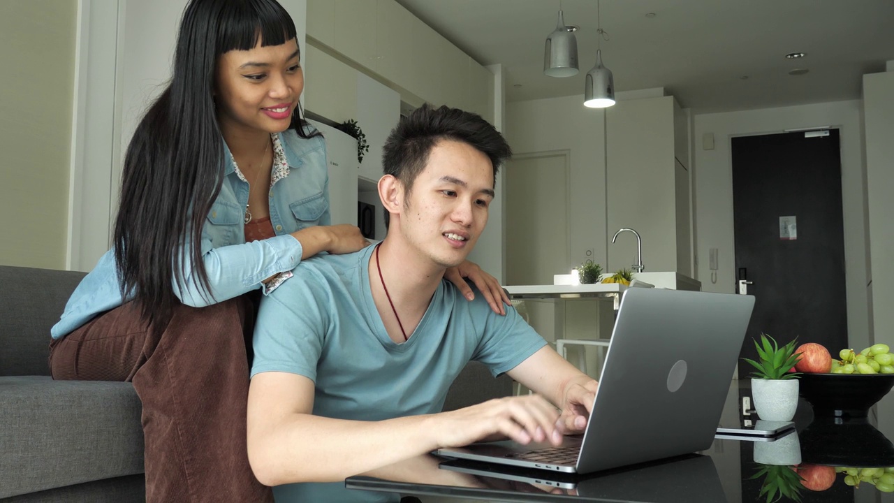 泛亚夫妇在家里用笔记本电脑远程工作或网上购物视频素材