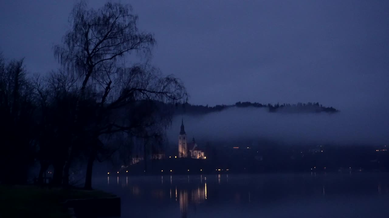斯洛文尼亚布莱德湖地标教堂城堡在岛上的灯光照亮在寒冷的冬夜低云山背景视频素材