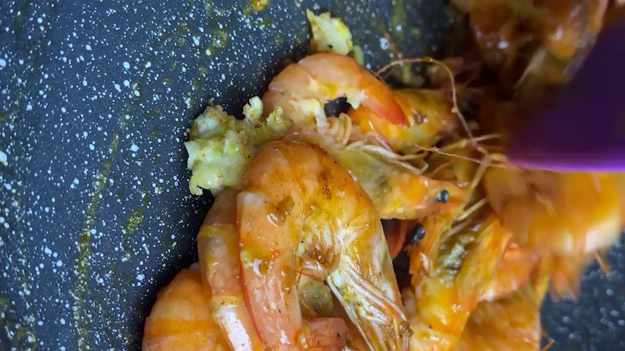 竖屏:用煎锅煎虾——特写。在煤气炉上用煎锅煮大虾。厨师用锅铲把虾和橄榄油混合在一起。烹饪海鲜。视频素材