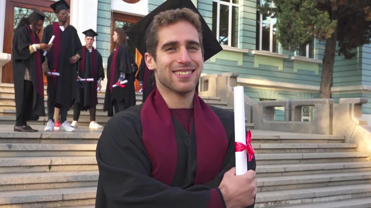 一个微笑的男毕业生拿着他的文凭视频素材