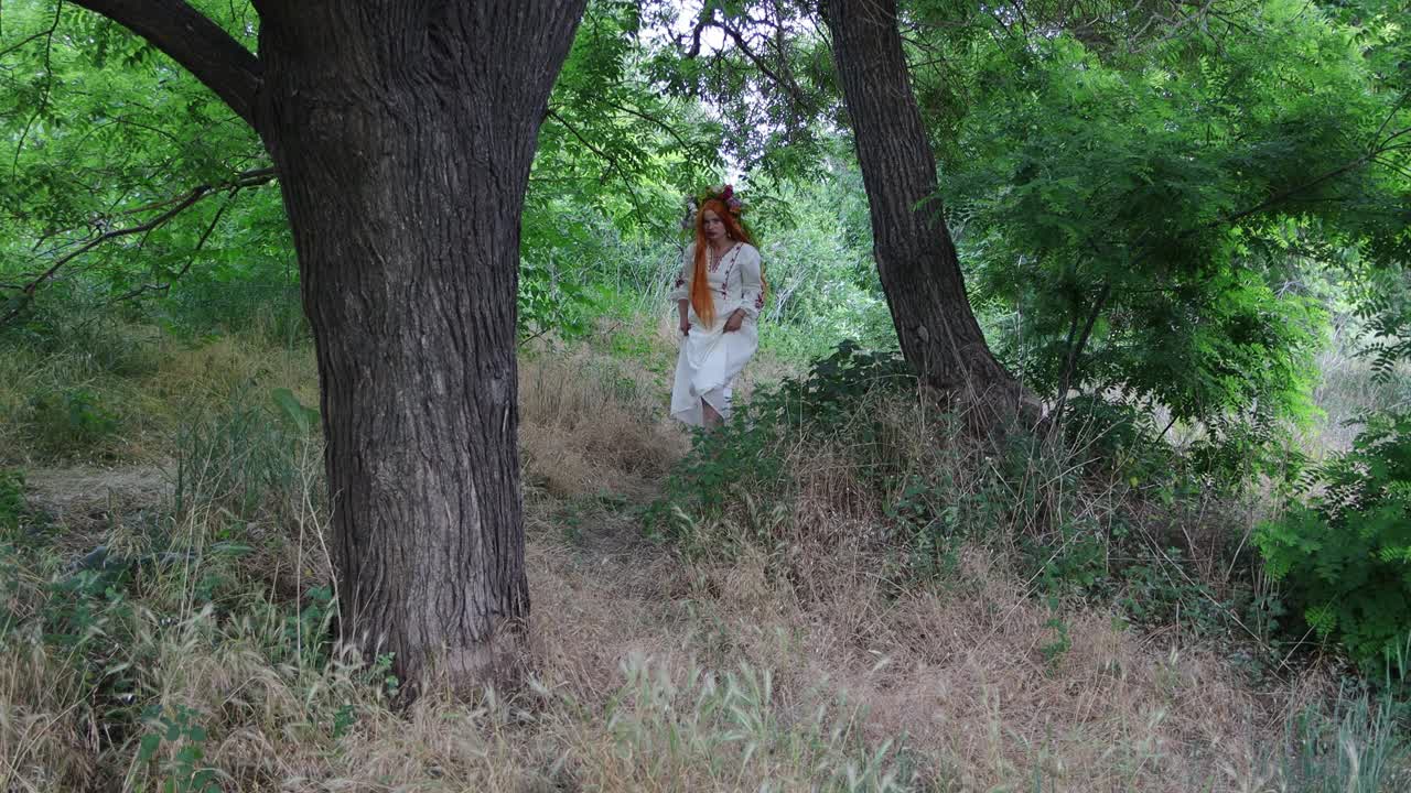 美丽的女孩，红色的长发，花冠，刺绣民族服装走出森林。异教信仰。童话人物，森林精灵，mavka，仙女。4 k的决议视频下载