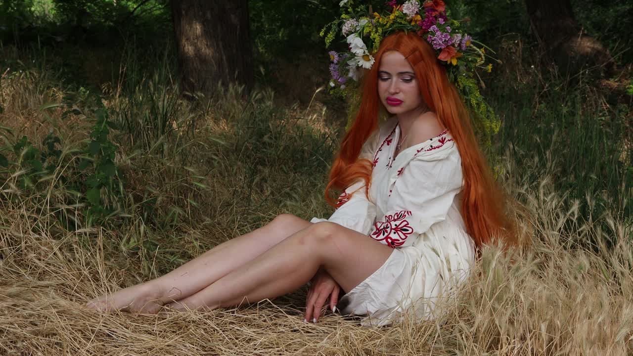 童话般的性格。美丽的女孩，红色的长发，戴着花冠，穿着刺绣的民族服装，坐在树林里。异教信仰。森林精灵，mavka，仙女。4 k的决议视频下载