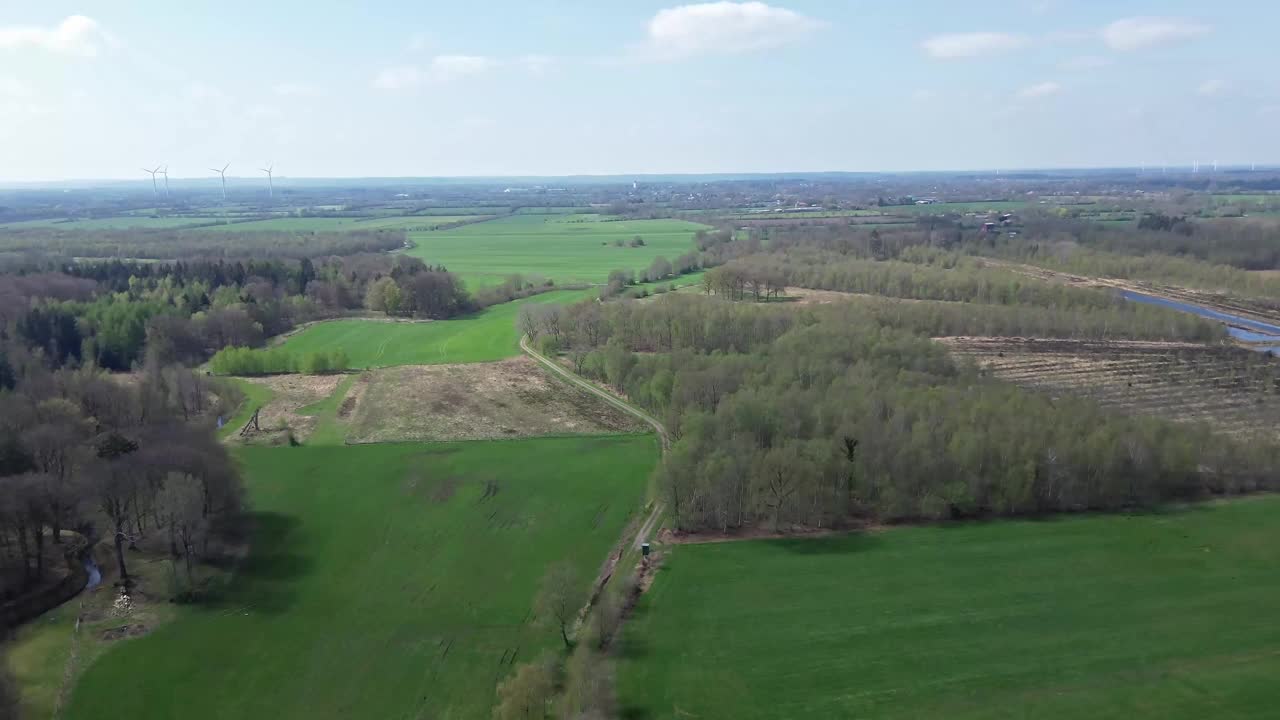 无人机拍摄的森林和农田的鸟瞰图，中间是小乡村道路和农场。视频素材