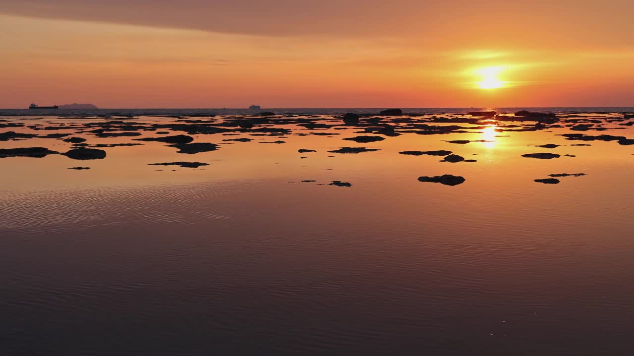 日落反射在海面上，就像镜子里的岩石出现在水面上。视频下载