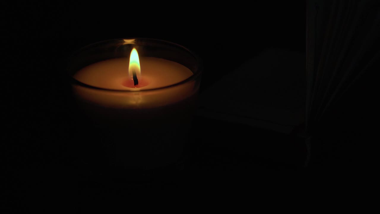 桌上燃着蜡烛，旁边放着一本打开的古老女巫书。视频素材