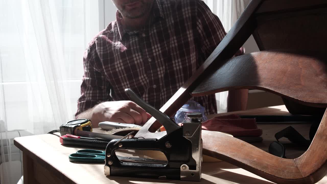 一名男子在一个小型家庭作坊里修理和修复家具。视频下载