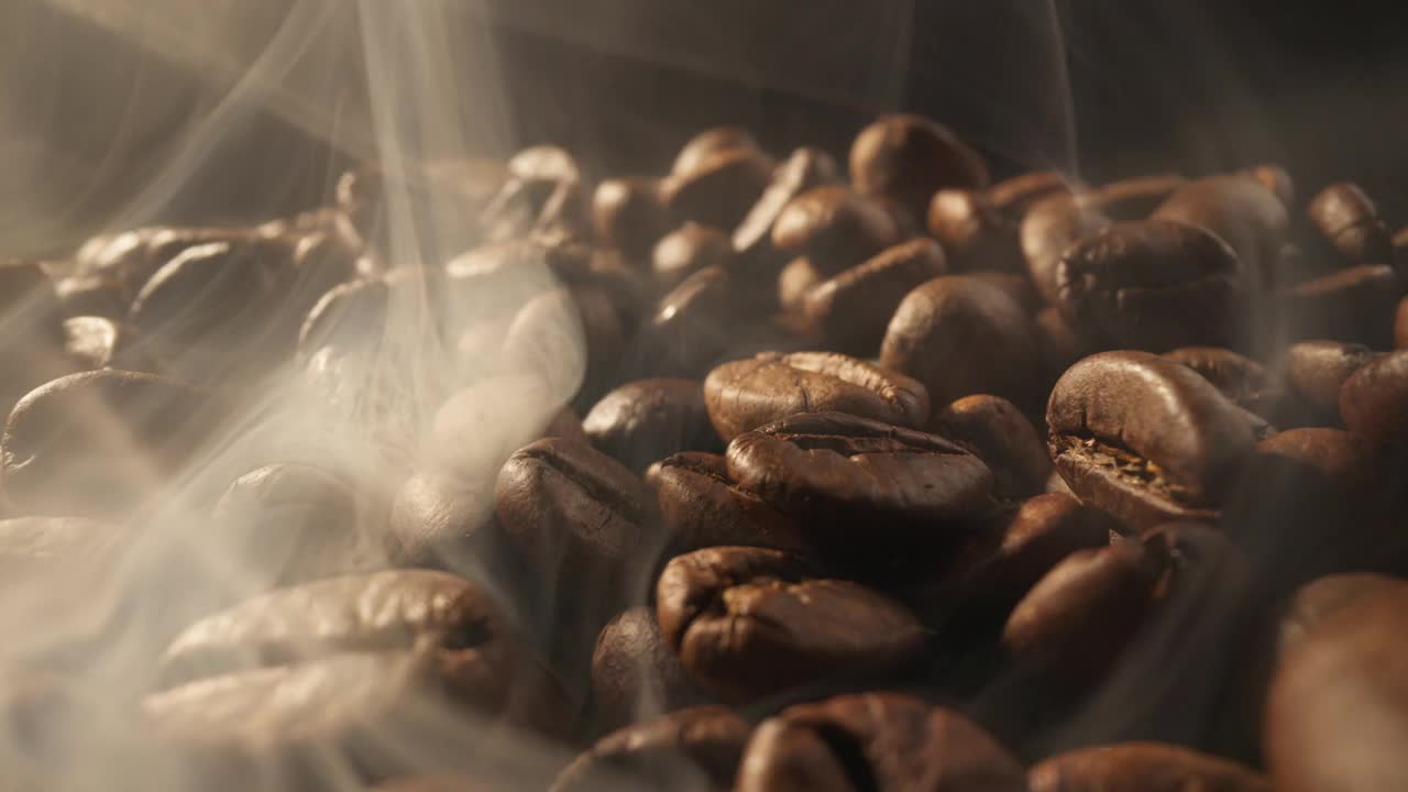 在黑背景下用烟熏咖啡豆。烟来自新鲜的咖啡籽视频素材