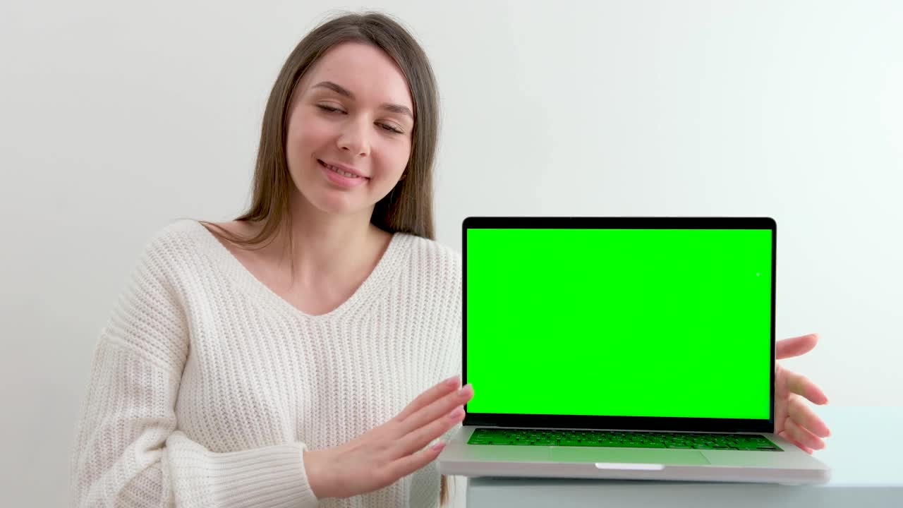 一个女商人在办公室内部的电脑上工作，看着绿色的屏幕。办公室人员使用笔记本电脑与笔记本电脑的绿色屏幕，坐在木桌视频下载