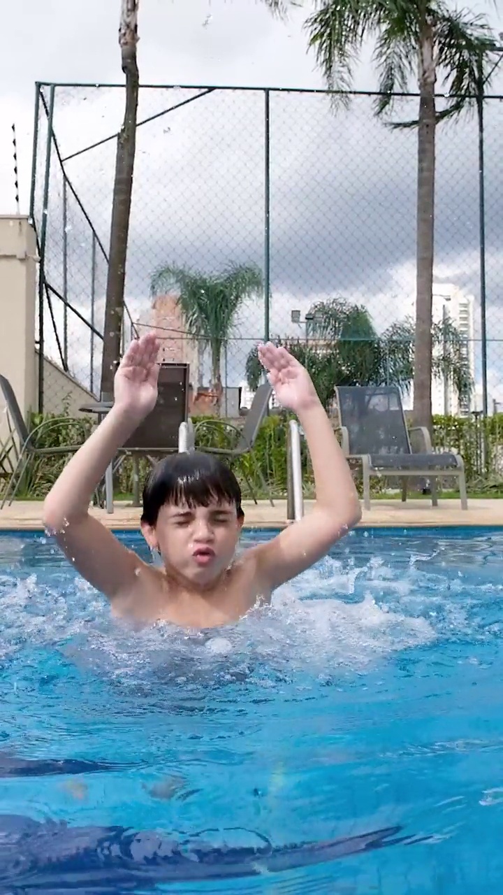 一个9岁的孩子在游泳池里以慢动作浮出水面并下沉。视频下载